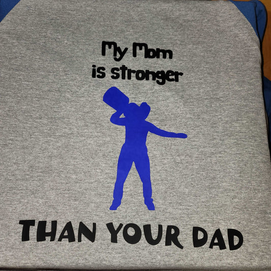 A high-quality raglan style shirt for kids, featuring a playful graphic of a strongwoman and the text "My Mom is Stronger than Your Dad