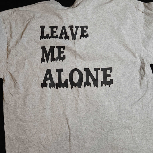 Black t-shirt with white text that reads "Leave Me Alone" in bold letters, with the Strongbox Apparel logo on the sleeve. Available in gray/black or black/red color options, and sizes ranging from small to 5x in a unisex cut. The message can be printed on the back or front of the tee, depending on customer preference