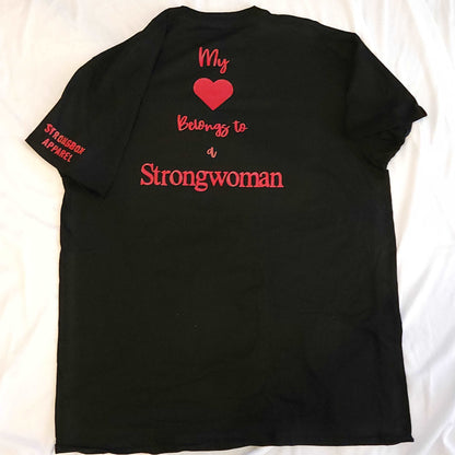 Black tee with a red cute print that says "My Heart Belongs to a Strongwoman." Available in ladies cut sizes small through 2X or unisex sizes small through 5X. Made from high-quality cotton and perfect for all-day wear. Option to add the print to the front